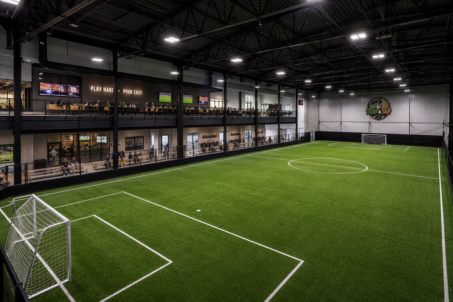 Turf & Tap — Full-size indoor turf field with viewing deck